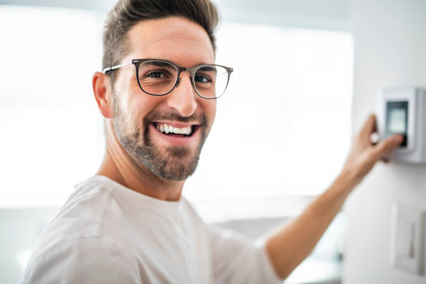 A Cheerful man set the thermostat at house