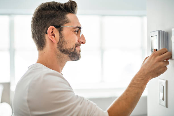 istock A Cheerful man set the thermostat at house 1074250574