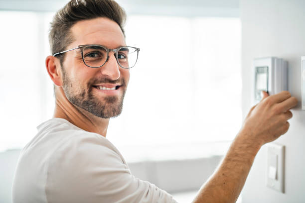 istock A Cheerful man set the thermostat at house 1074250576