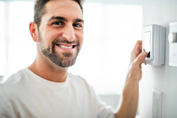 istock A Cheerful man set the thermostat at house 1074250590