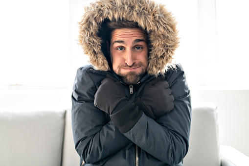 Man have cold on the sofa at home with winter coat
