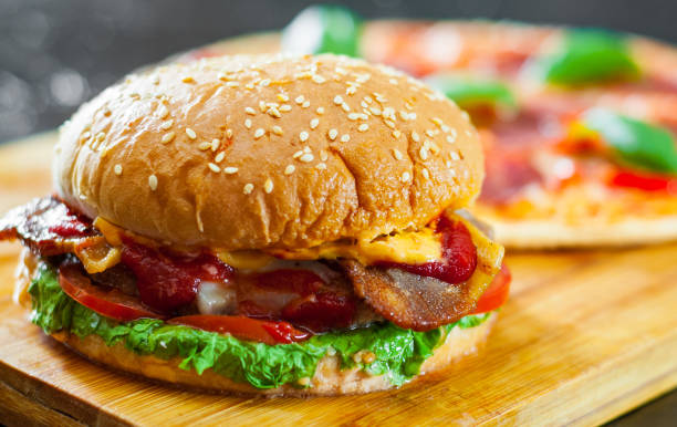 istock bacon cheese burger with beef patty tomato onion and Pizza with Mozzarella cheese, Ham, Tomatoes, salami, pepper, pepperoni Spices and Fresh Basil 1074255394