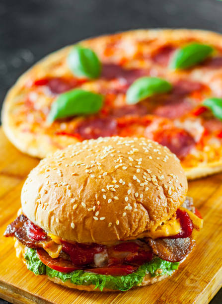 istock bacon cheese burger with beef patty tomato onion and Pizza with Mozzarella cheese, Ham, Tomatoes, salami, pepper, pepperoni Spices and Fresh Basil 1074255454