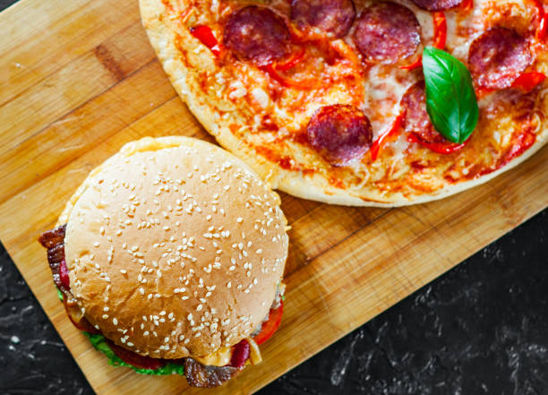 istock bacon cheese burger with beef patty tomato onion and Pizza with Mozzarella cheese, Ham, Tomatoes, salami, pepper, pepperoni Spices and Fresh Basil 1074255462