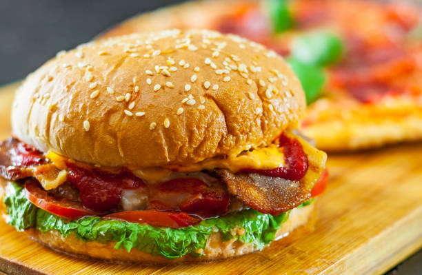 istock bacon cheese burger with beef patty tomato onion and Pizza with Mozzarella cheese, Ham, Tomatoes, salami, pepper, pepperoni Spices and Fresh Basil 1074257100