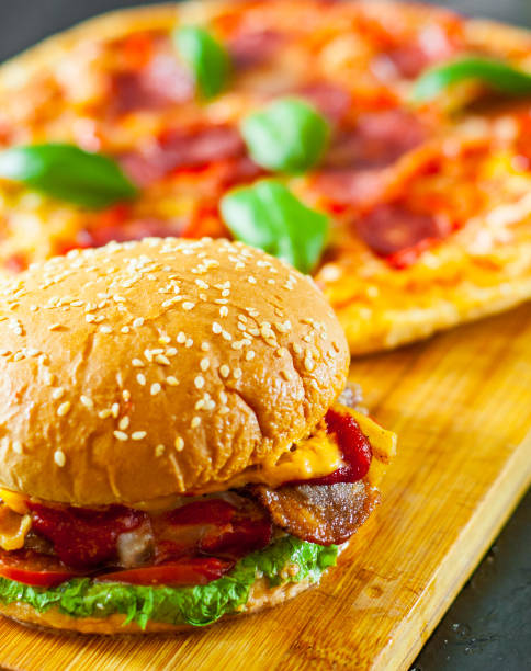 istock bacon cheese burger with beef patty tomato onion and Pizza with Mozzarella cheese, Ham, Tomatoes, salami, pepper, pepperoni Spices and Fresh Basil 1074257102