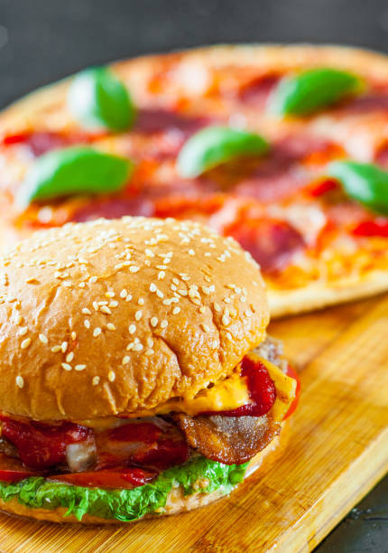 istock bacon cheese burger with beef patty tomato onion and Pizza with Mozzarella cheese, Ham, Tomatoes, salami, pepper, pepperoni Spices and Fresh Basil 1074257152