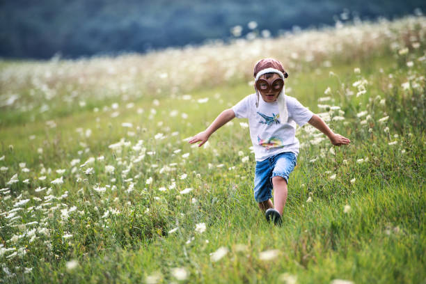 istock A small boy with pilot goggles and hat running in nature on a summer day. 1074264796
