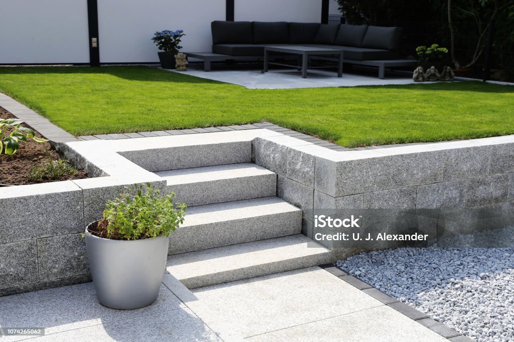 Neat and tidy garden with granite wall and solid block steps Yard - Grounds Stock Photo