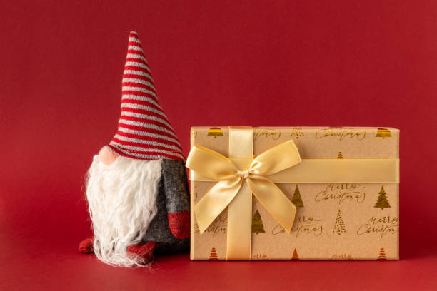 istock Christmas decoration with a gnome and a gift box on red background 1074269250