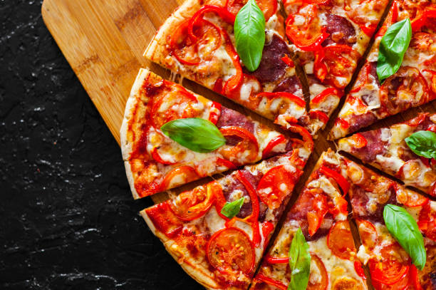 istock Pizza with Mozzarella cheese, Ham, Tomatoes, salami, pepper, pepperoni Spices and Fresh Basil. Italian pizza 1074269822