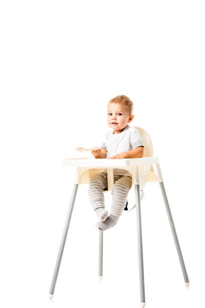 cute toddler boy sitting in highchair and looking at camera isolated on white cute toddler boy sitting in highchair and looking at camera isolated on white high chair stock pictures, royalty-free photos & images