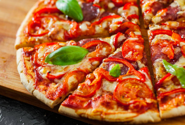 istock Pizza with Mozzarella cheese, Ham, Tomatoes, salami, pepper, pepperoni Spices and Fresh Basil. Italian pizza 1074272352