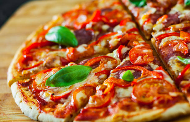 istock Pizza with Mozzarella cheese, Ham, Tomatoes, salami, pepper, pepperoni Spices and Fresh Basil. Italian pizza 1074272522