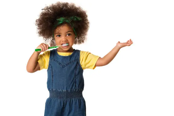 Photo of A little cute african american girl brushing her teeth, isolated