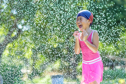 little girls happiness in the spray water, she dance and smiling