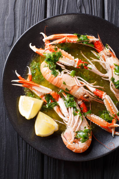 istock Cooked scampi or langoustine close-up on a plate with sauce and lemon. Vertical top view 1074278708