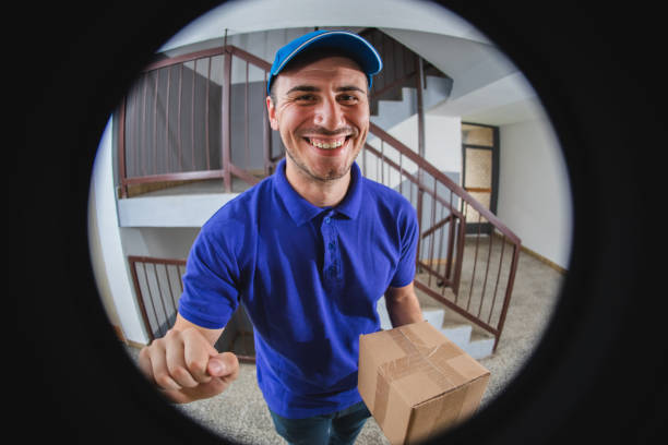 Postman with package at the door Young man delivering package at the door peep hole stock pictures, royalty-free photos & images