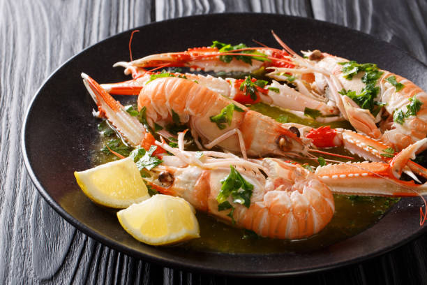 istock Served boiled langoustines, Dublin Bay prawn, scampi with lemon and melted butter with herbs close-up on a black table. Horizontal 1074280124