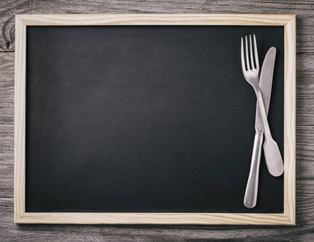istock Empty menu blackboard with knife and fork on wooden background. Food background 1074282730