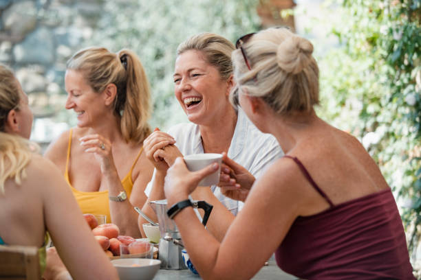Mature Women Enjoying Holiday Breakfast Mature women are socialising over breakfast in the courtyard of their holiday villa in Italy. outdoor dining photos stock pictures, royalty-free photos & images