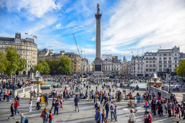 gente del posto e turisti che visitano e frequentaro trafalgar square nella city of westminster, londra, inghilterra, regno unito - il monumento di nelson foto e immagini stock