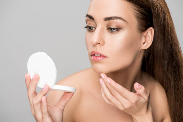istock elegant young woman looking at mirror, isolated on grey 1074286774