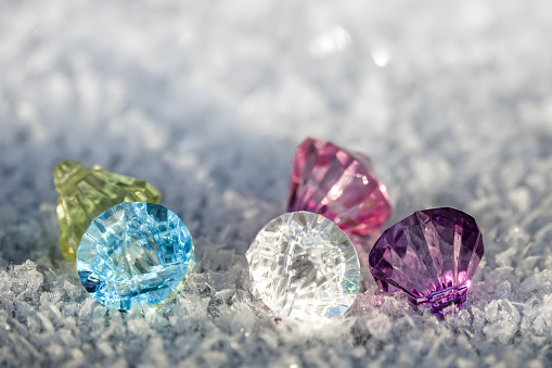 Colorful diamonds and frozen crystals on frost and snow in the sun outdoors.