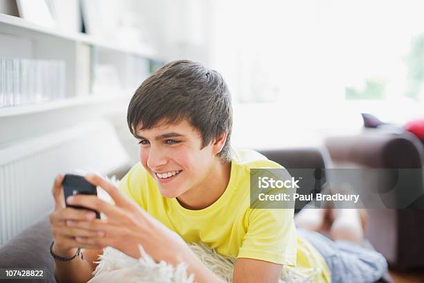 Photo libre de droit de Jeune Garçon Souriant Dans La Salle De Séjour De Sms banque d'images et plus d'images libres de droit de Jeunes garçons