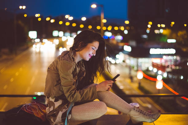 istock Woman in the city by night texting 1074288232