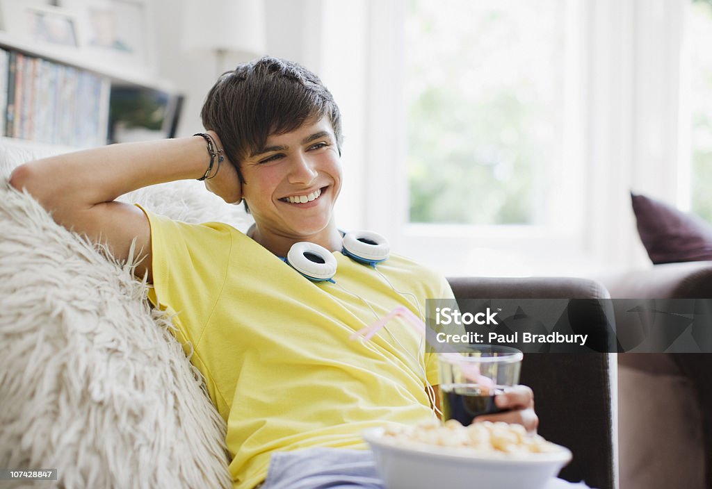 Uśmiechająca się nastoletni chłopiec siedzi z popcorn i sody - Zbiór zdjęć royalty-free (Nastoletni chłopcy)