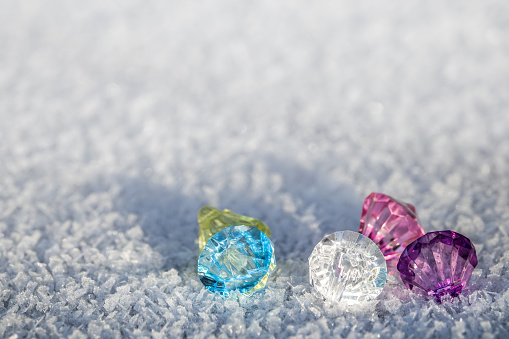 Colorful diamonds and frozen crystals on frost and snow in the sun outdoors. Empty background for copy space.