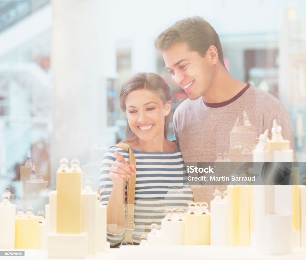 Sonriente pareja mirando a la joyería en carcasa de display - Foto de stock de Hombres libre de derechos