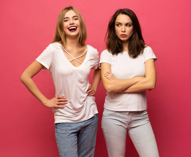 deux demoiselles en colère debout sur fond rose - beautiful lifestyles human face blond hair photos et images de collection