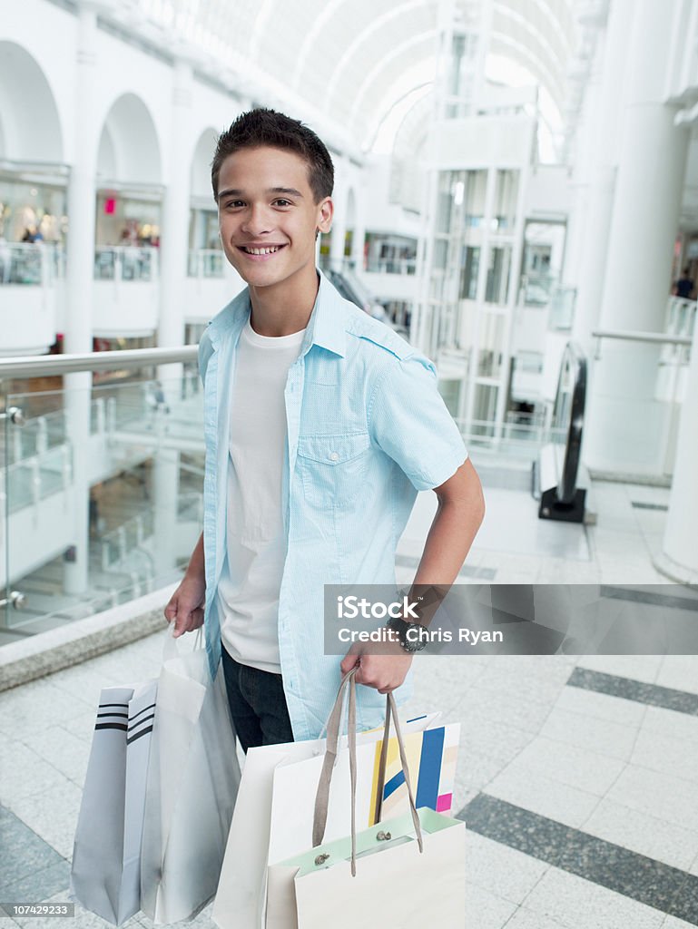 Souriant homme transportant des sacs de shopping au centre commercial - Photo de Centre commercial libre de droits