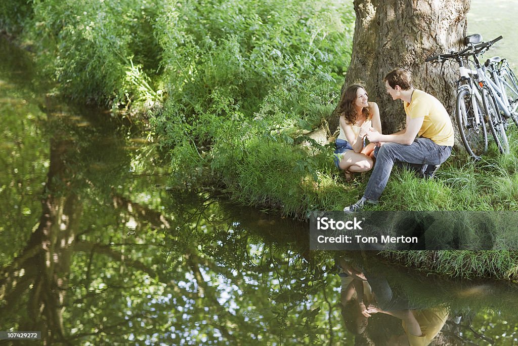 Couple avec vélos ensemble assis sur la rive - Photo de Ruisseau libre de droits