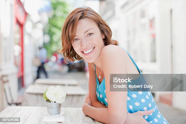 Mujer Sonriente Sentado En La Mesa Del Café Foto de stock y más banco de imágenes de Cabello corto - Cabello corto, Citas románticas, Mujeres