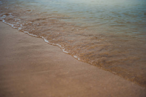 istock Soft Wave Of Blue Ocean On Sandy Beach. Background. Selective focus. 1074295654