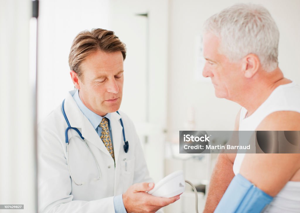 Pazienti medico prendendo la pressione sanguigna in ufficio medici - Foto stock royalty-free di Misuratore di pressione sanguigna