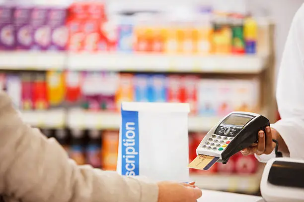 Photo of Pharmacist holding security device for customer in drug store