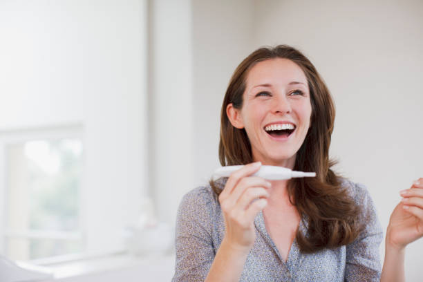 feliz mujer agarrando prueba de embarazo - prueba de embarazo fotografías e imágenes de stock