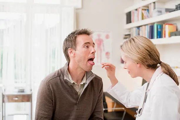 Photo of Doctor examining patients throat in doctors office
