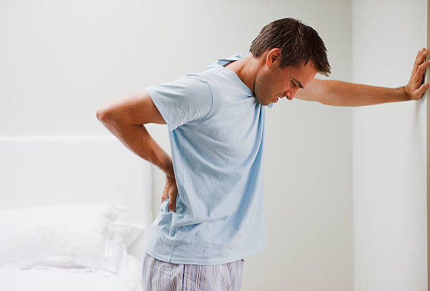Man with backache leaning against wall  back pain stock pictures, royalty-free photos & images