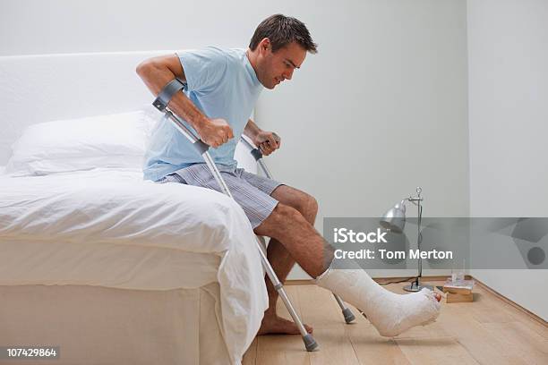 Человек С Сломанная Нога Пытается Встать С Кровати — стоковые фотографии и другие картинки Сломанная нога - Сломанная нога, Мужчины, Исцеление