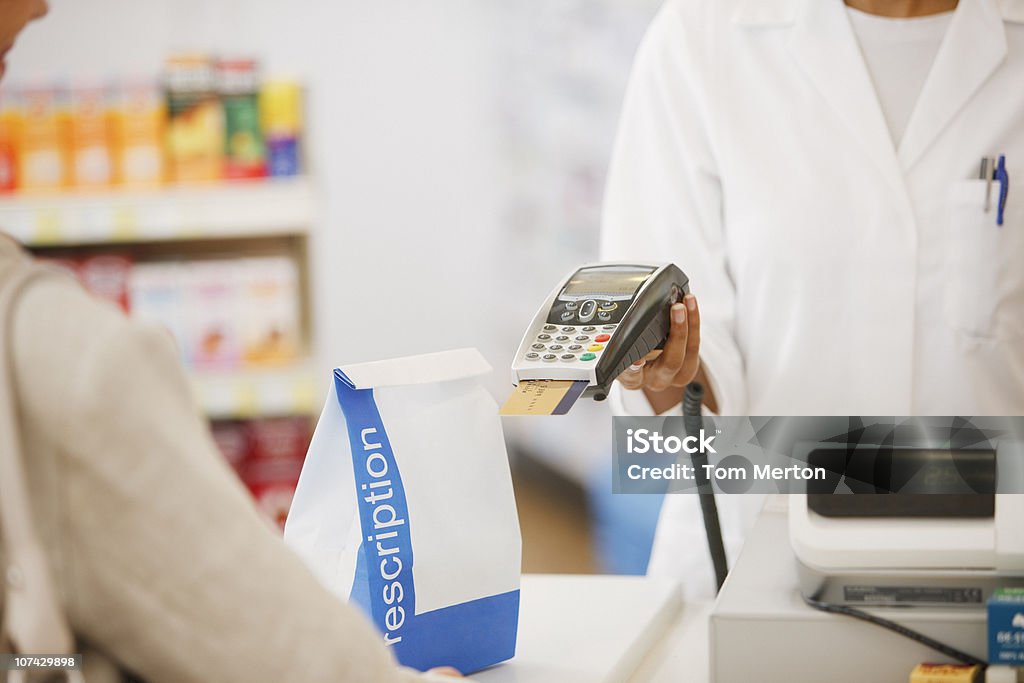 Farmacéutico de retención de un dispositivo de seguridad para el cliente en farmacia - Foto de stock de Farmacia libre de derechos