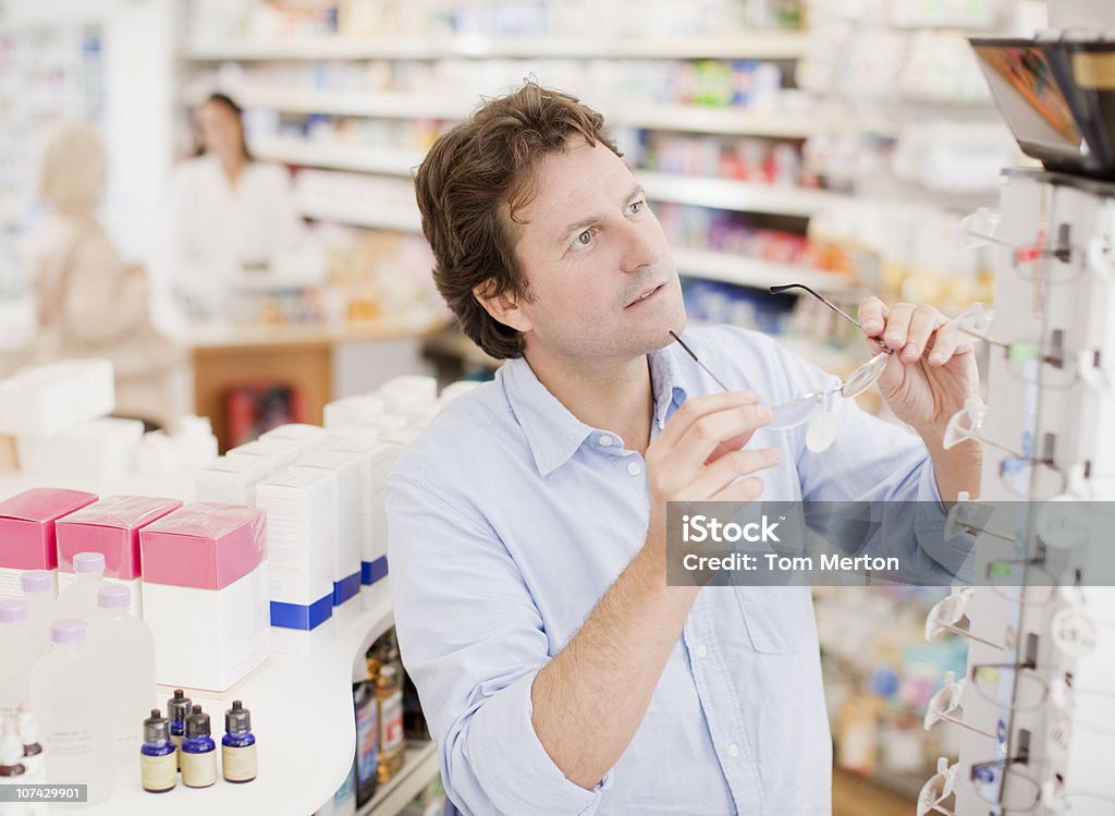 Il cliente sta cercando su Occhiali da vista farmaco in negozio - Foto stock royalty-free di Occhiali da lettura