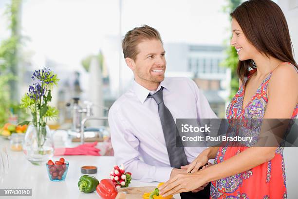 Marido Hablando De Mujer Mientras La Paciente Parte De Las Verduras En La Cocina Foto de stock y más banco de imágenes de 25-29 años