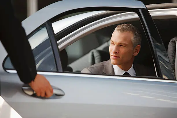 Photo of Chauffeur opening car door for businessman