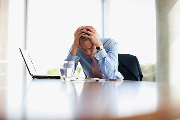 Frustrated businessman with head in hands at desk  head in hands stock pictures, royalty-free photos & images