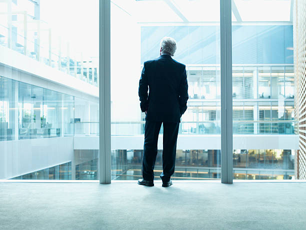 Businessman looking out glass wall in office  ceo stock pictures, royalty-free photos & images